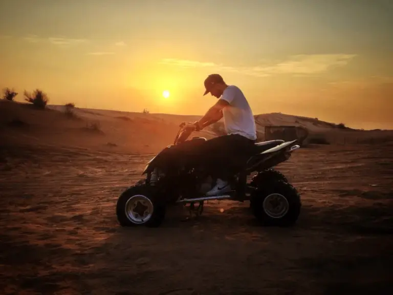 A person driving a buggy across sand dunes.