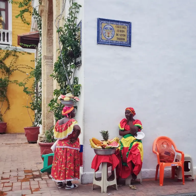 Palenqueras standing in front of a white wall in Cartagena, Colombia.
