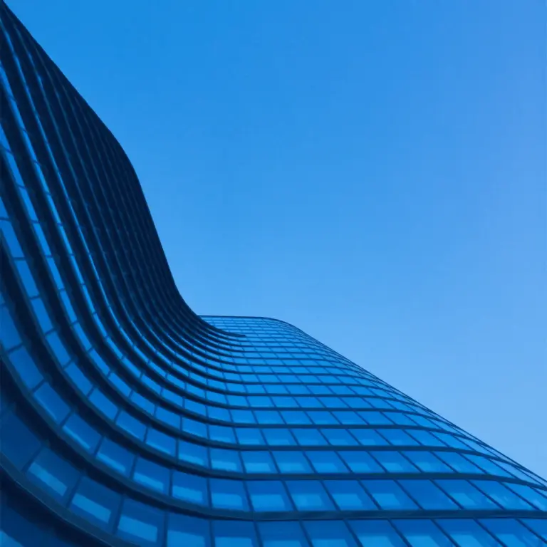 View from the base of a skyscraper looking straight up, with blue-toned glass.