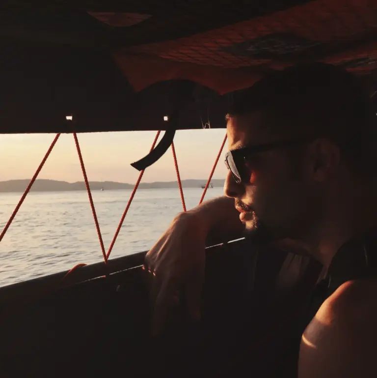 Person with sunglasses sitting inside a boat in Thailand enjoying the view.